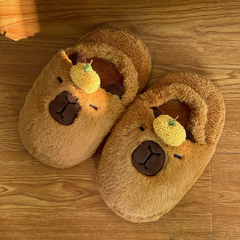 Pair of brown capybara slippers with fluffy texture on a wooden surface