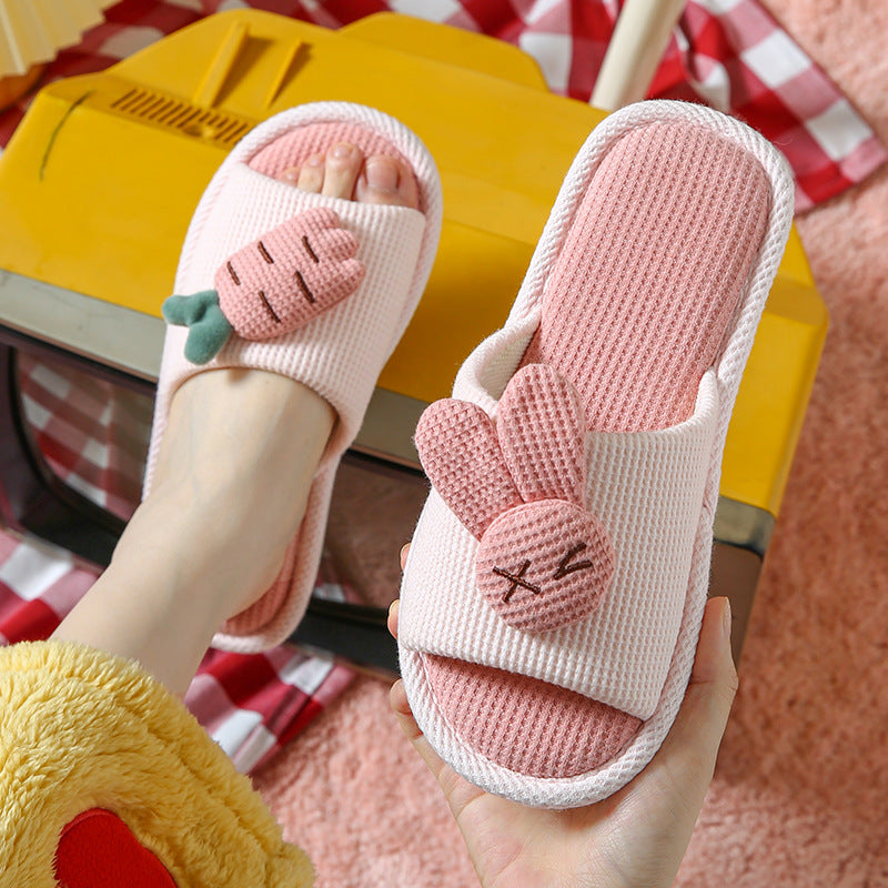 Pink slippers with bunny ears held by a hand on a checkered floor.