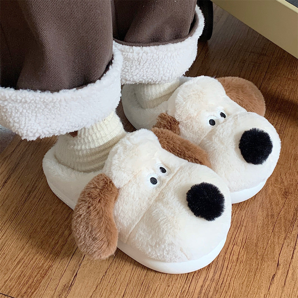Pair of dog-shaped slippers held in front of a kitchen background