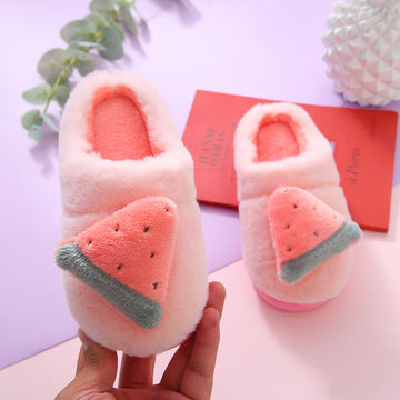 Pair of pink slippers with watermelon design held by a hand on a light purple background.