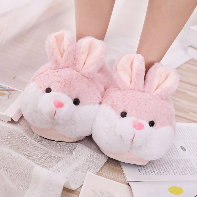 Pink rabbit slippers worn by a person on a light wooden floor.