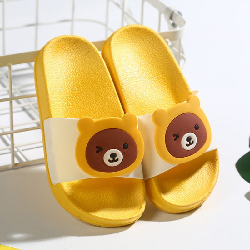 Yellow slippers with bear face design on a white background