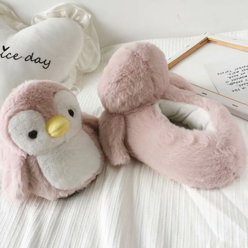 Pink plush penguin slippers on a white surface