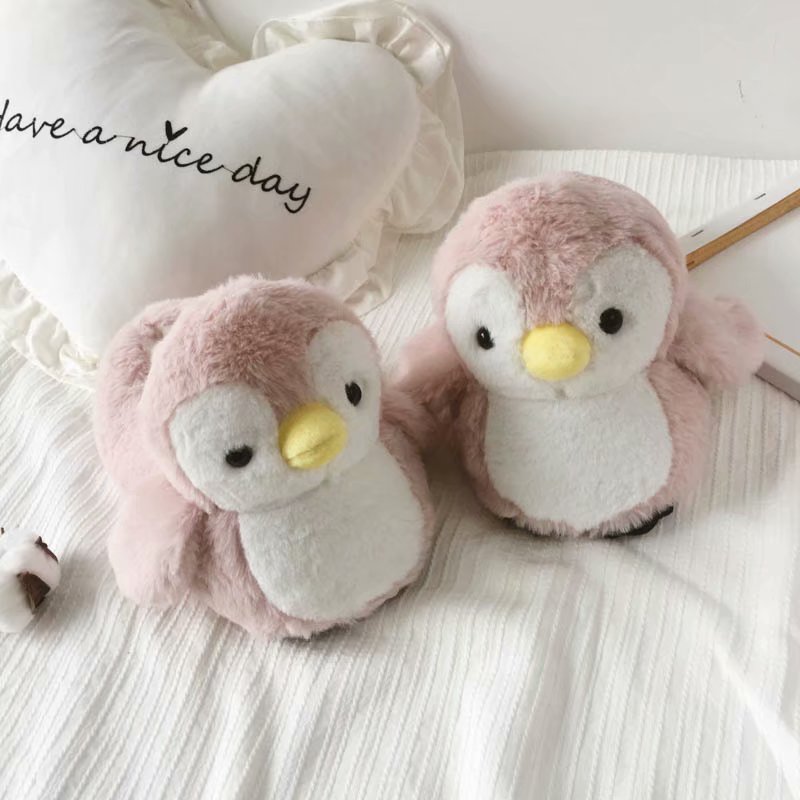 Four plush penguin slipper in gray and pink on a white surface with a soft focus background.