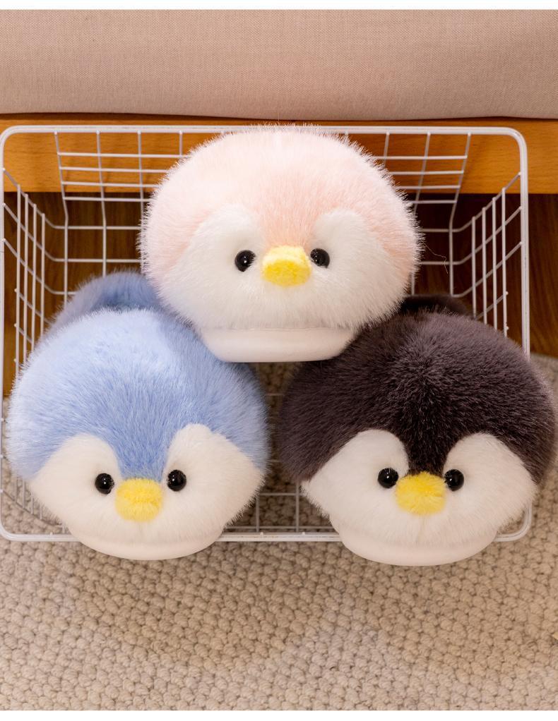 Three plush penguin slippers in different colors on a wire rack.