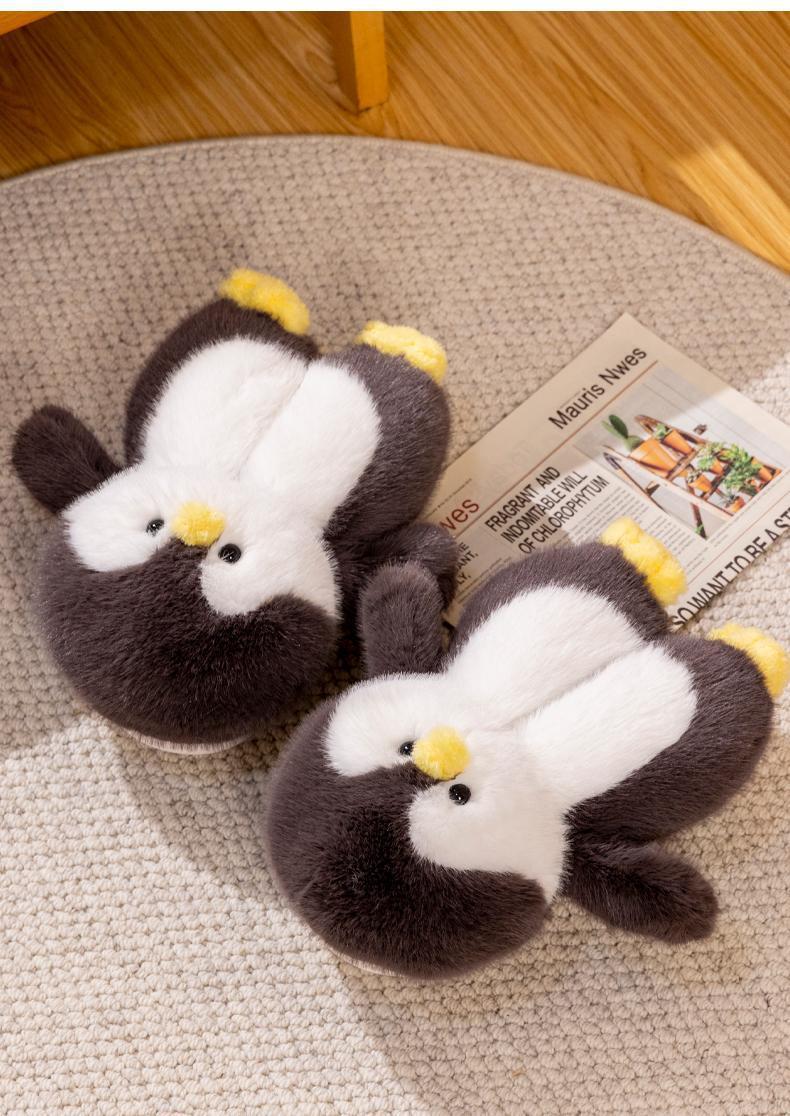 Pair of penguin-shaped slippers on a textured surface with a newspaper underneath.
