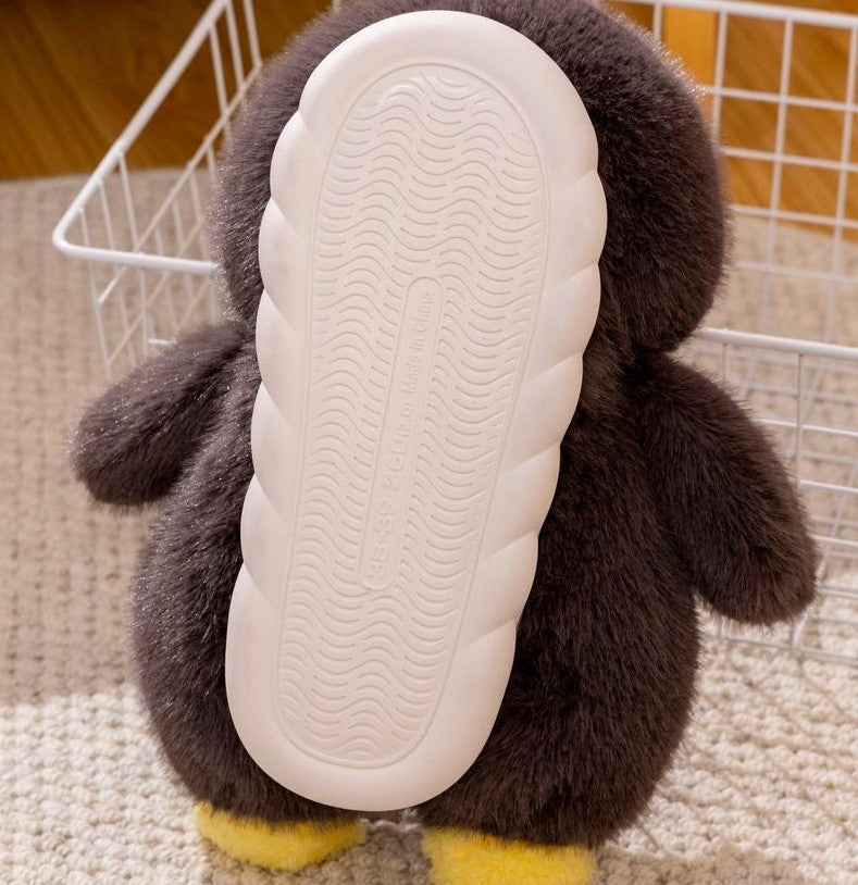 Penguin-shaped plush slipper with a back white sole on a carpeted floor.