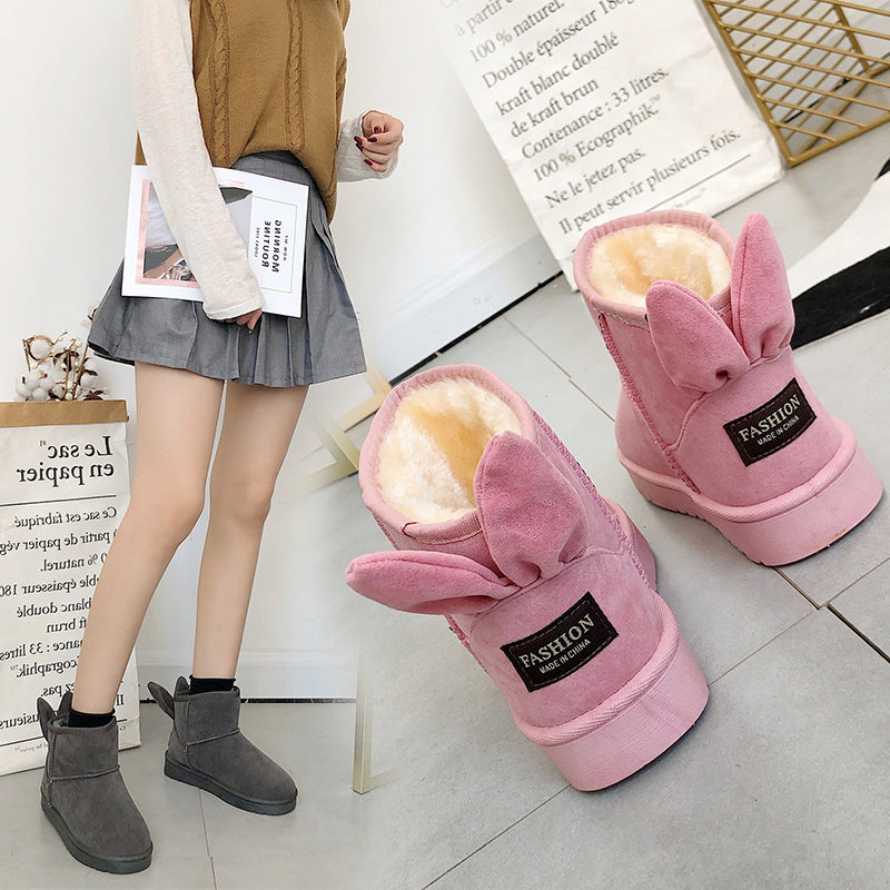 Pink bunny ear boots with a person wearing gray boots in the background.
