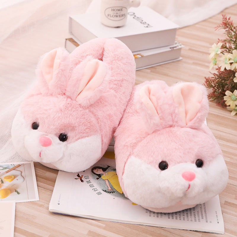 Pink bunny slippers on a wooden surface with a book and small plant in the background.