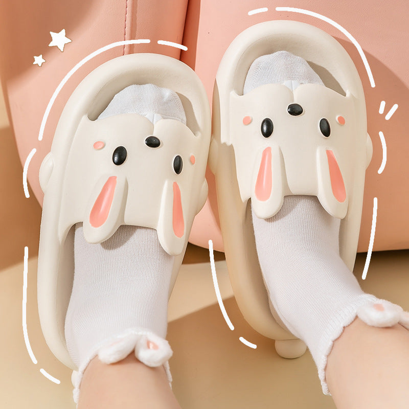 Pair of bunny white slippers with black eyes and pink accents on a beige background.