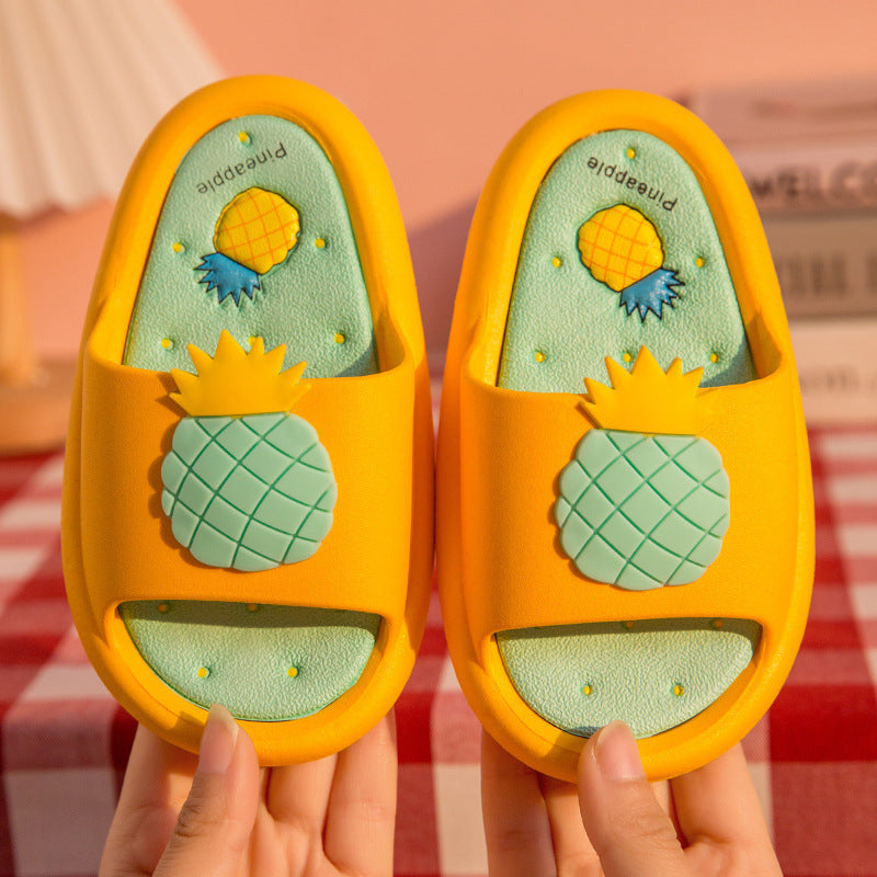 Pair of pineapple-themed slippers held by a person against a striped background
