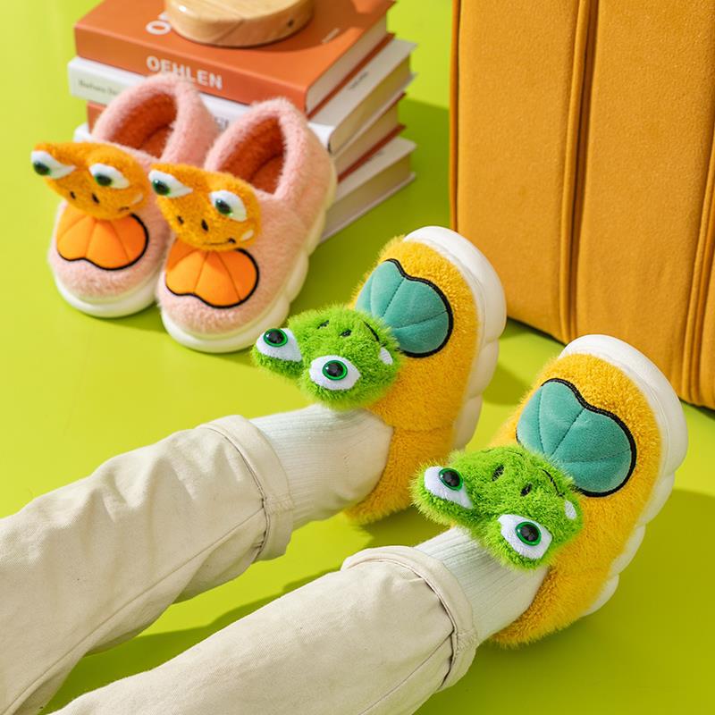 Children's frog slippers on a green surface.