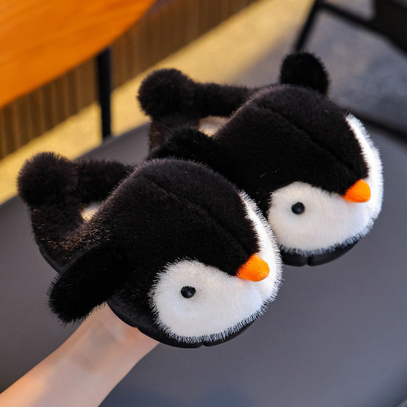 Pair of penguin-themed slippers on a surface with a blurred background