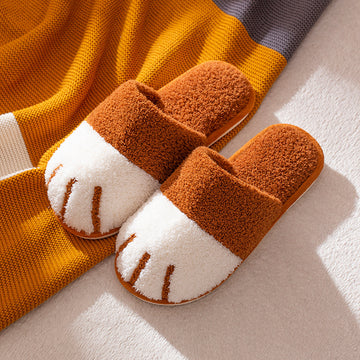 Pair of brown and white slippers on a light surface with a striped fabric background.
