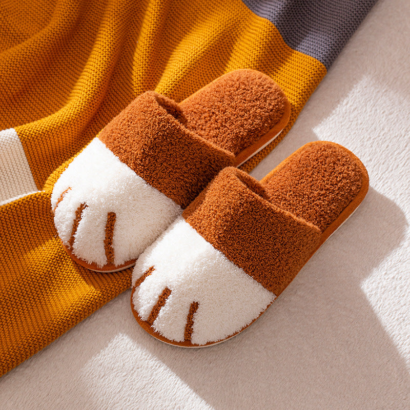 Pair of brown and white slippers on a light surface with a striped fabric background.
