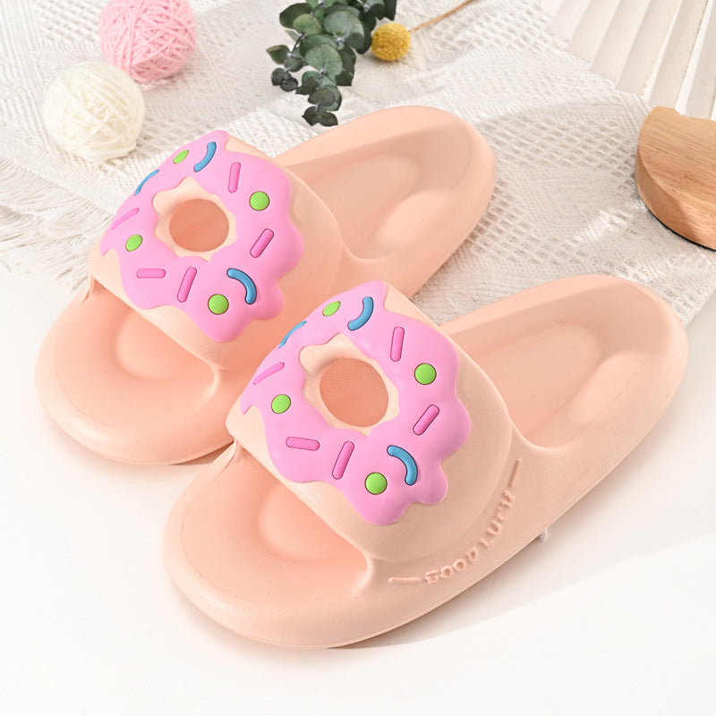 Pink donut-themed slippers on a white surface with decorative elements.