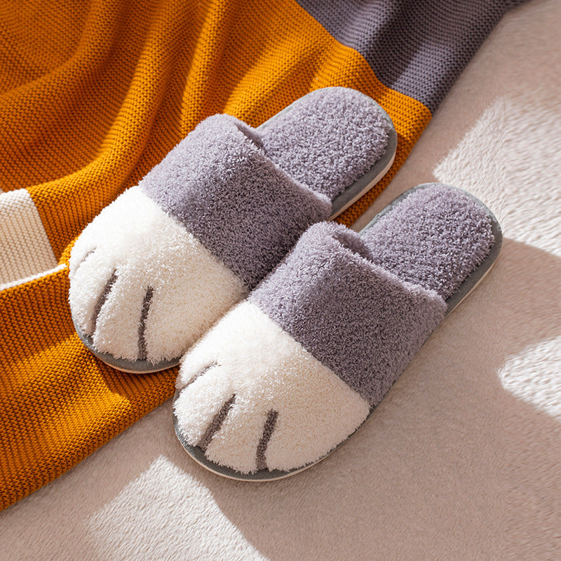 Pair of gray and white slippers with paw design on a soft surface.