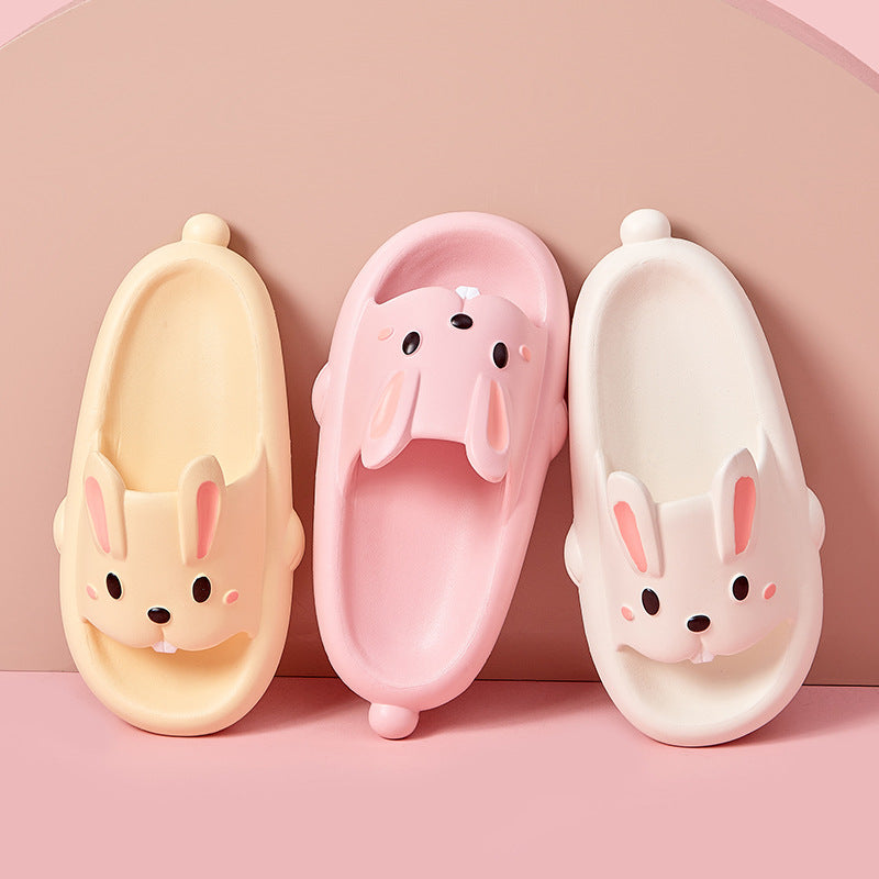 Three bunny face slippers in yellow, pink, and white on a pink background