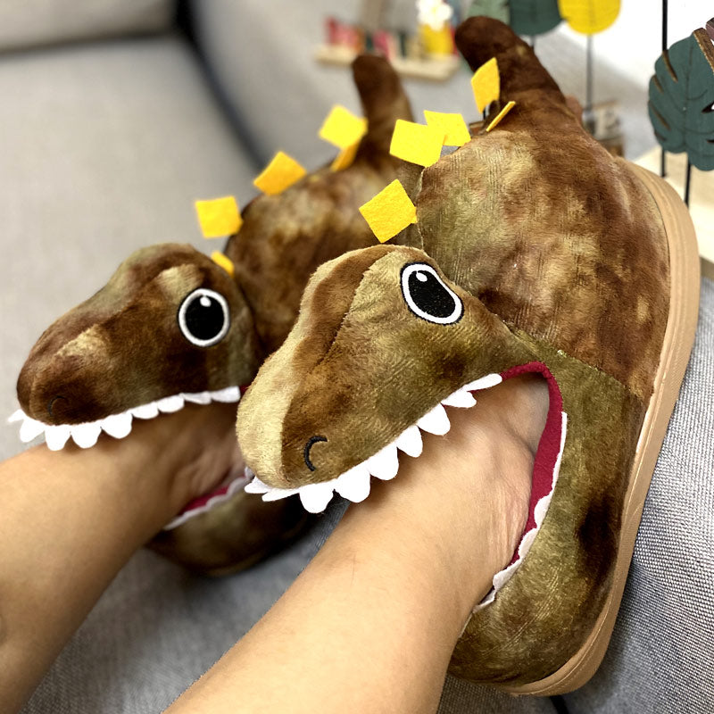 Green dinosaur-shaped slippers on a gray surface with a blurred background
