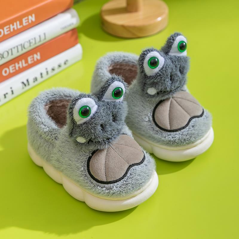 Pair of gray plush slippers with frog design on a green surface