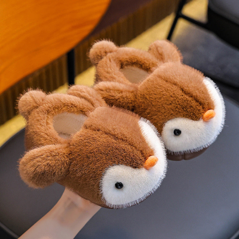 Pair of brown plush penguin slippers on a dark surface.
