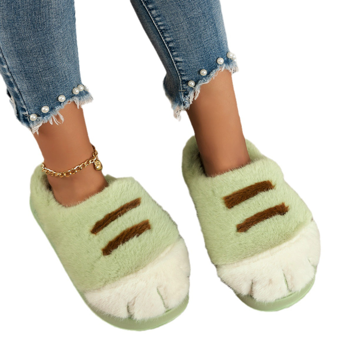 Green slippers with paw design worn by a person wearing blue jeans.