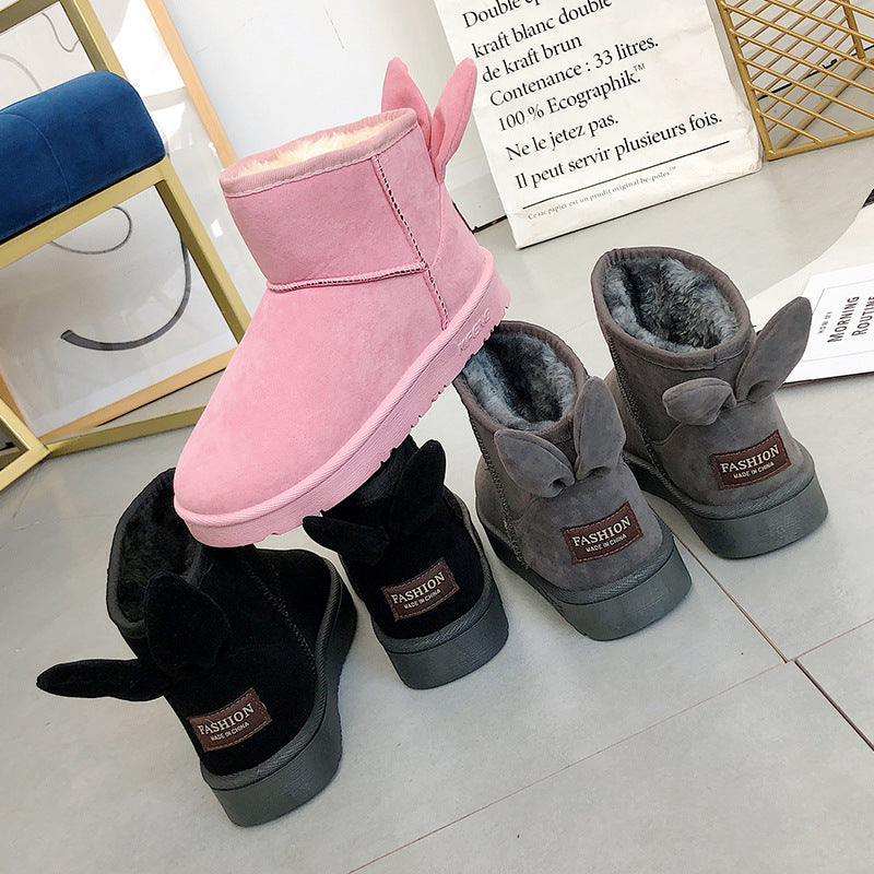 Pink, gray, and black bunny ear boots on a white surface with a blurred background.