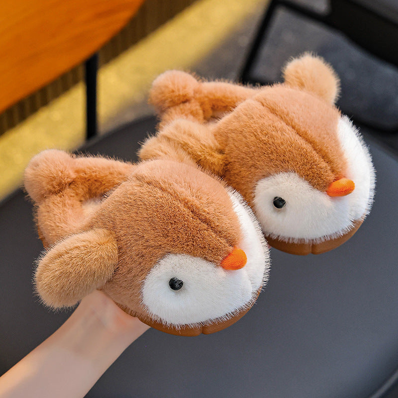 Pair of plush penguin slippers on a dark surface.