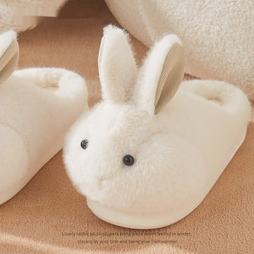 White rabbit-shaped plush slippers on a brown surface