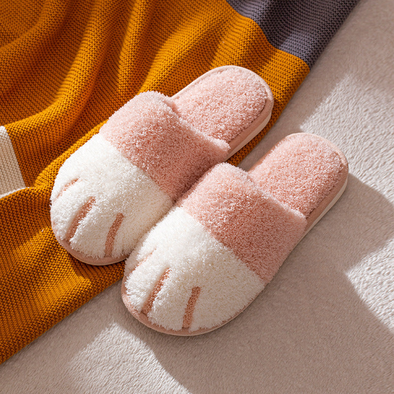 Pair of pink and white slippers on a textured surface with a colorful blanket.