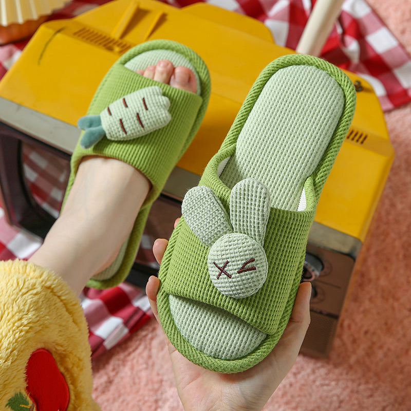 Green slippers with bunny design held by a hand, against a red and white checkered background.