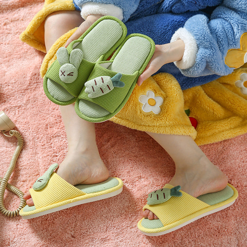 Children's green and yellow slippers with rabbit design on a pink carpet.