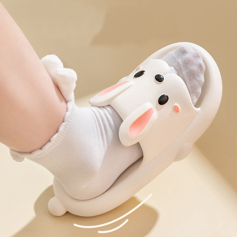 Children's white slipper with bunny design worn by a child on a beige background