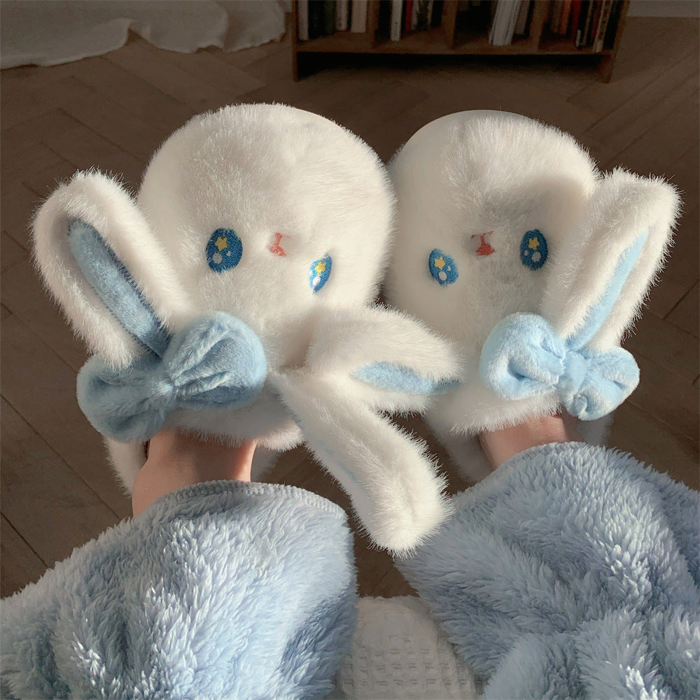 White plush slippers with blue bows held by a person wearing a matching robe.