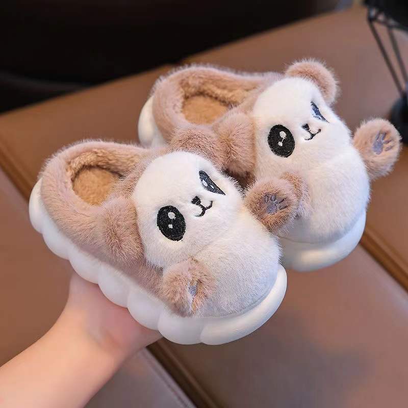 Pair of khaki panda slippers with animal faces held by a hand.