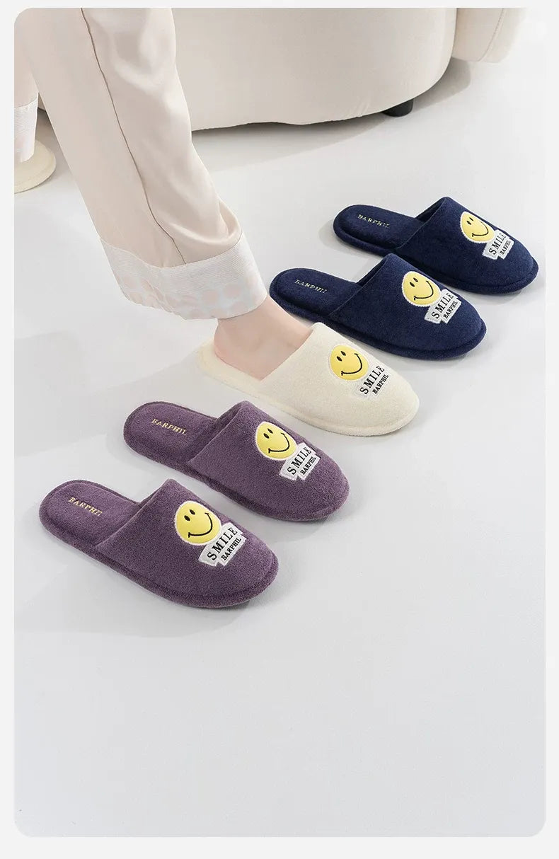 Four pairs of slippers with smiley face designs on a light background
