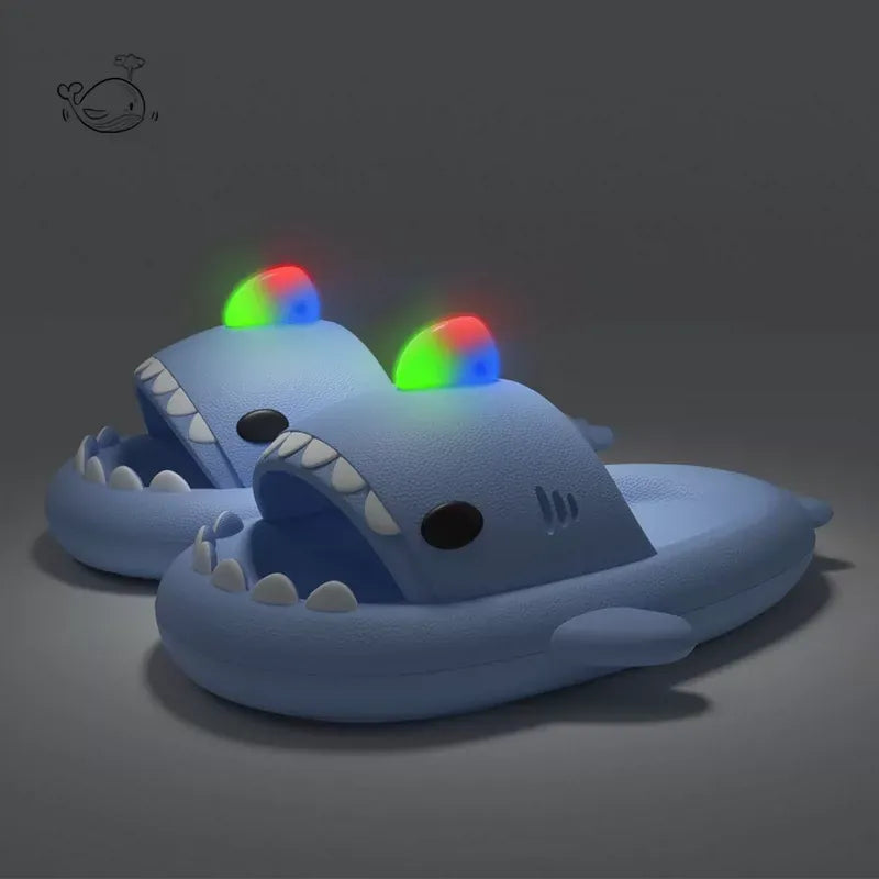 Blue shark-shaped slippers with colorful LED lights on a dark background
