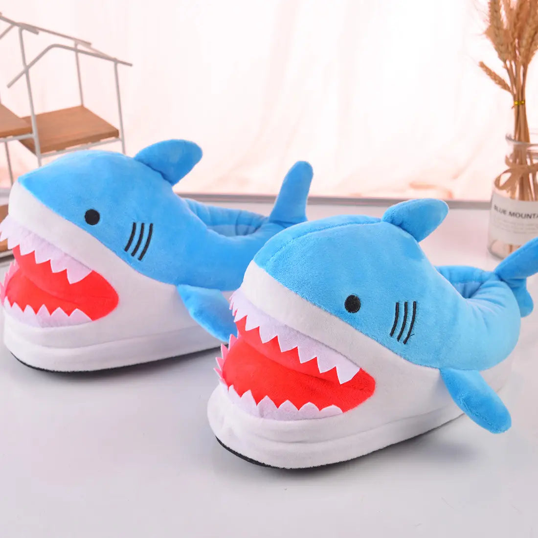 Shark-themed slippers on a light surface with a blurred background