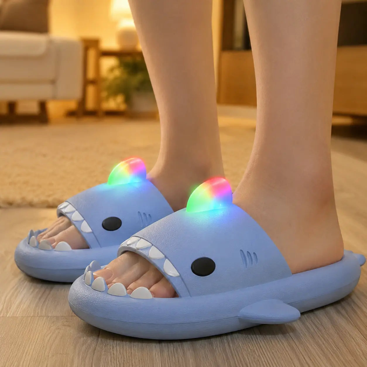 Blue shark-shaped slippers with LED lights on a wooden floor.
