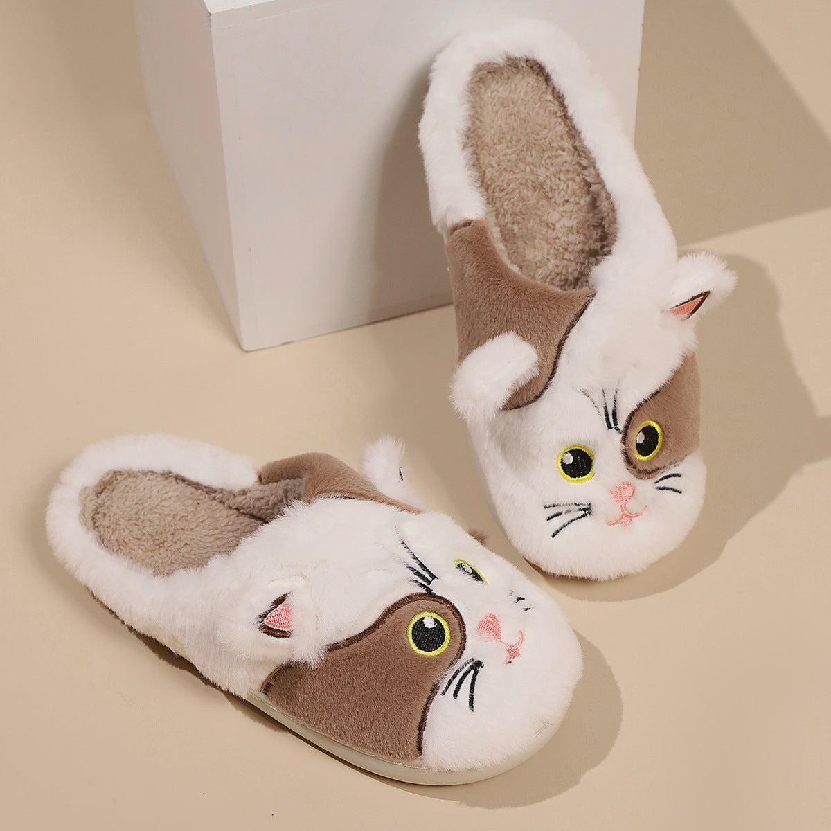 Cat-shaped slippers with facial features on a beige background