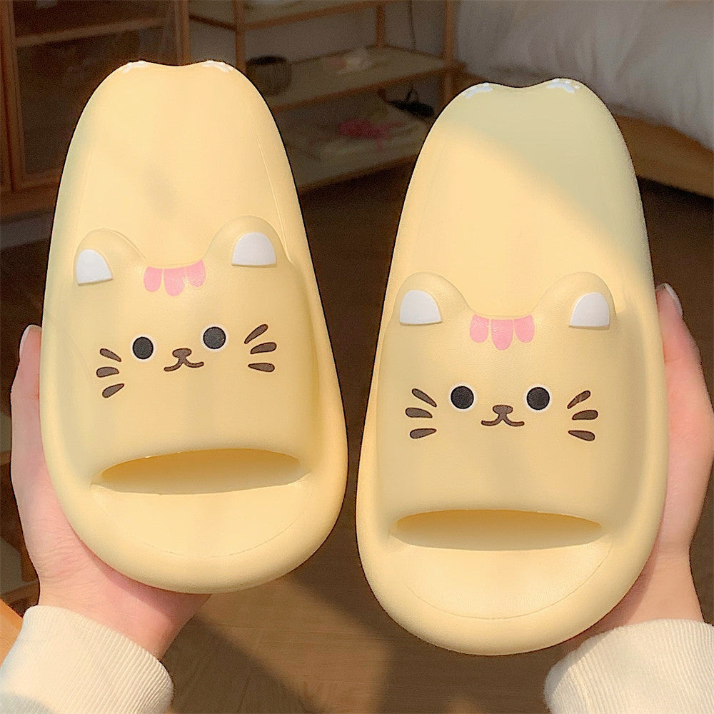 Pair of cute cat-shaped slippers held by a person indoors.