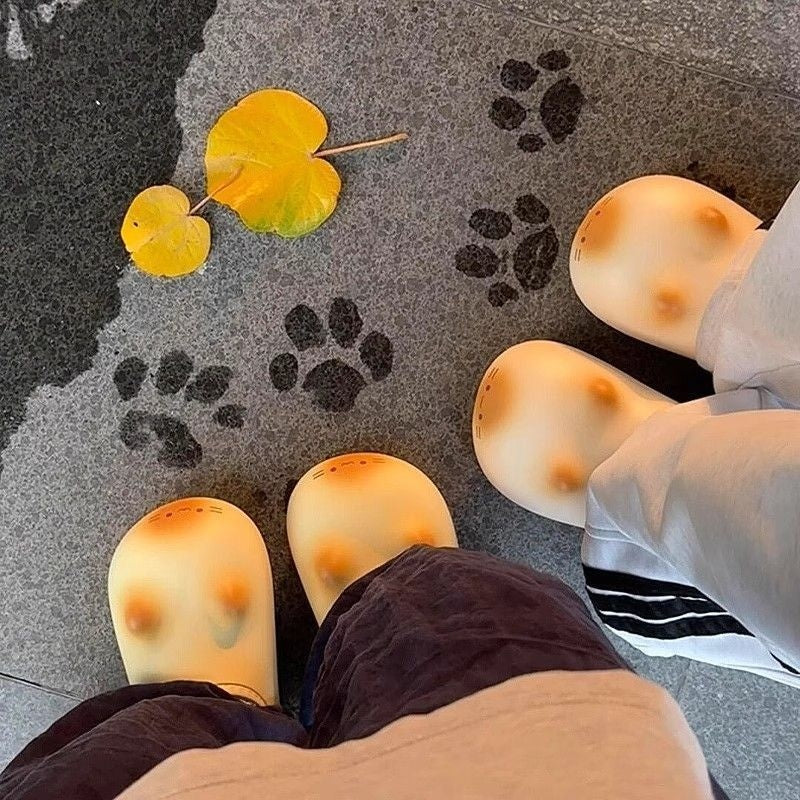 Feet wearing socks with a pattern of black paw prints on a gray surface with yellow leaves.