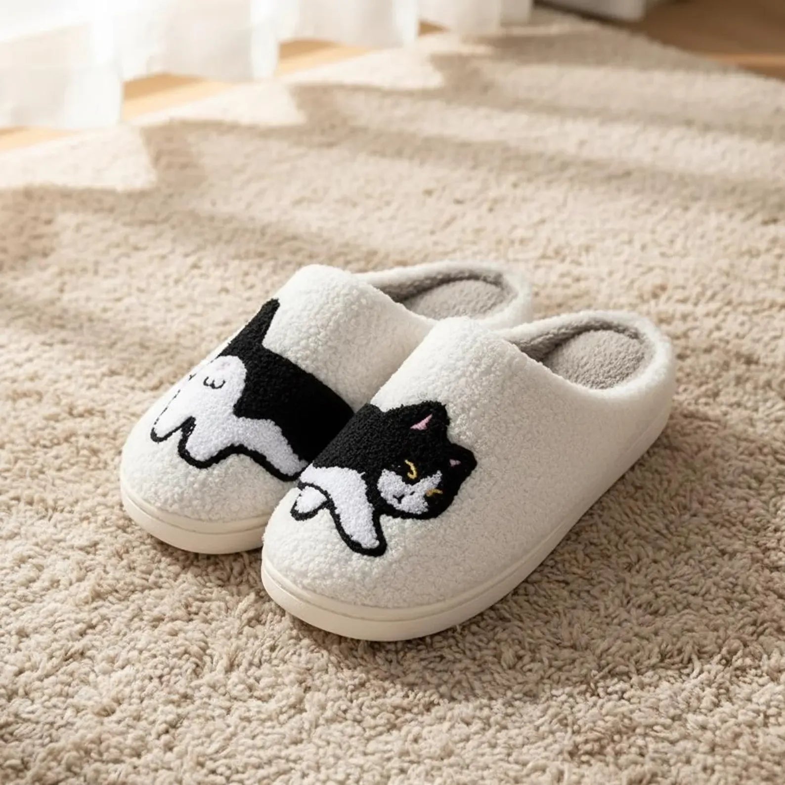 Pair of white slippers with cat designs on a beige carpet