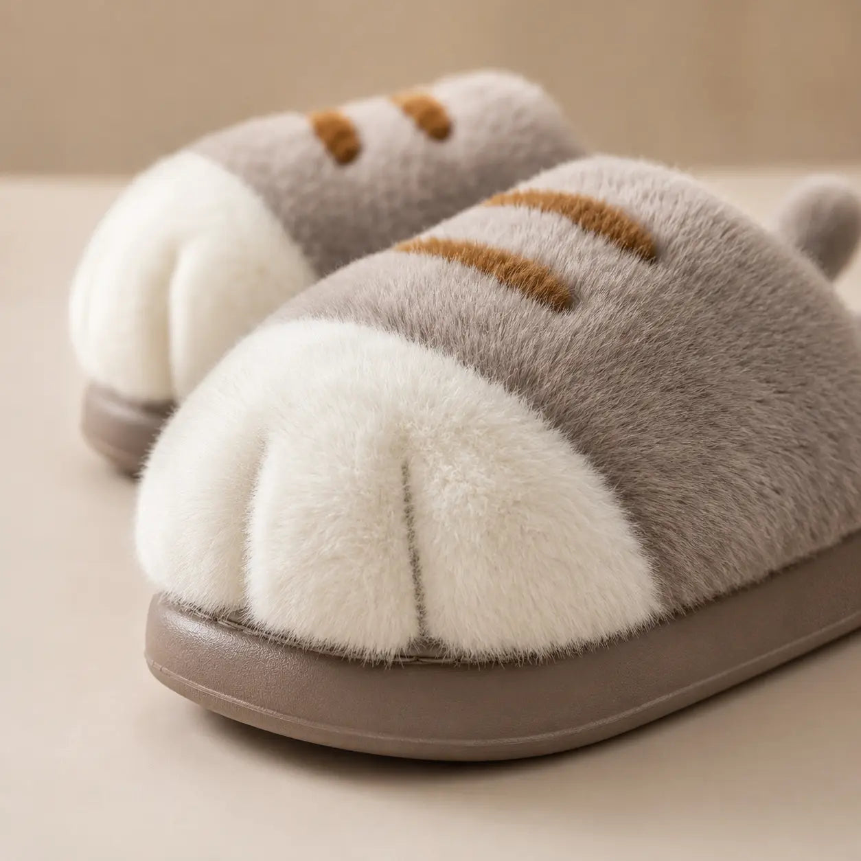 Pair of fluffy slippers with a cat design on a beige background