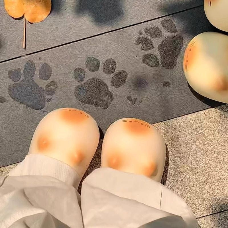 Paw prints on a doormat with a person wearing white pants standing on the mat.