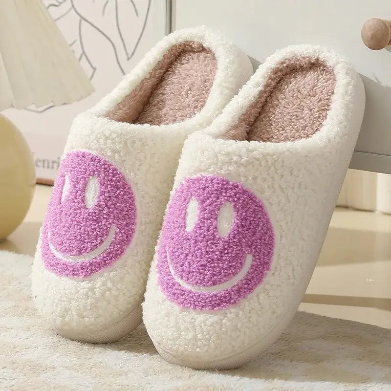 White slippers with pink smiley faces on a soft surface