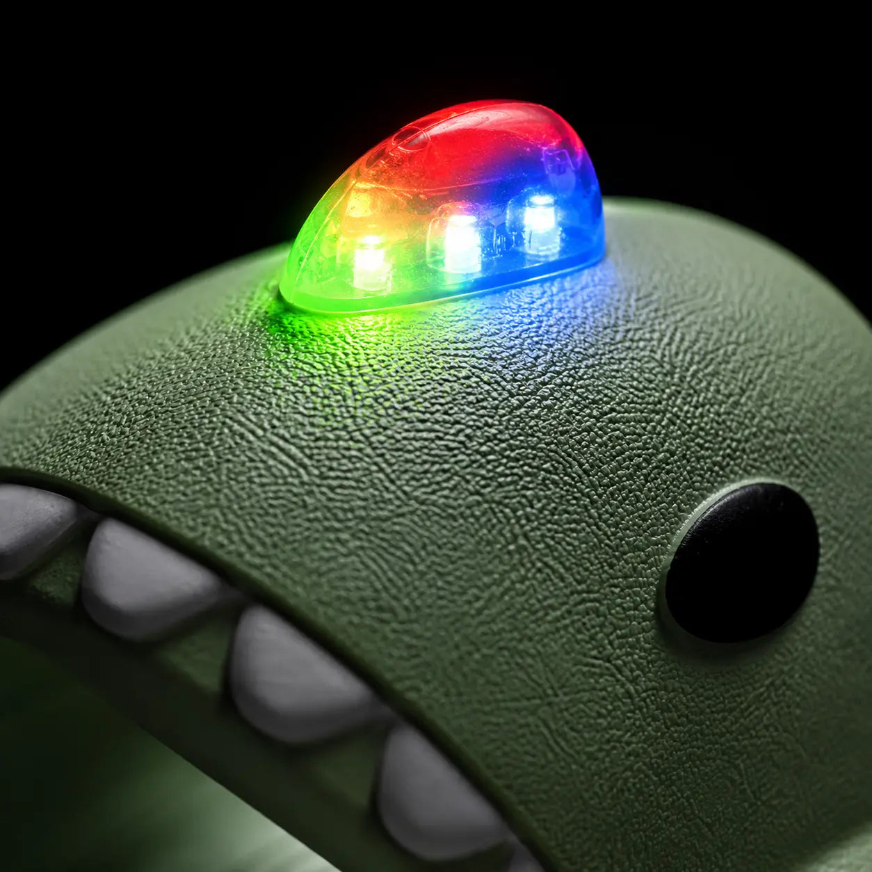 Green toy with a colorful LED light on a black background