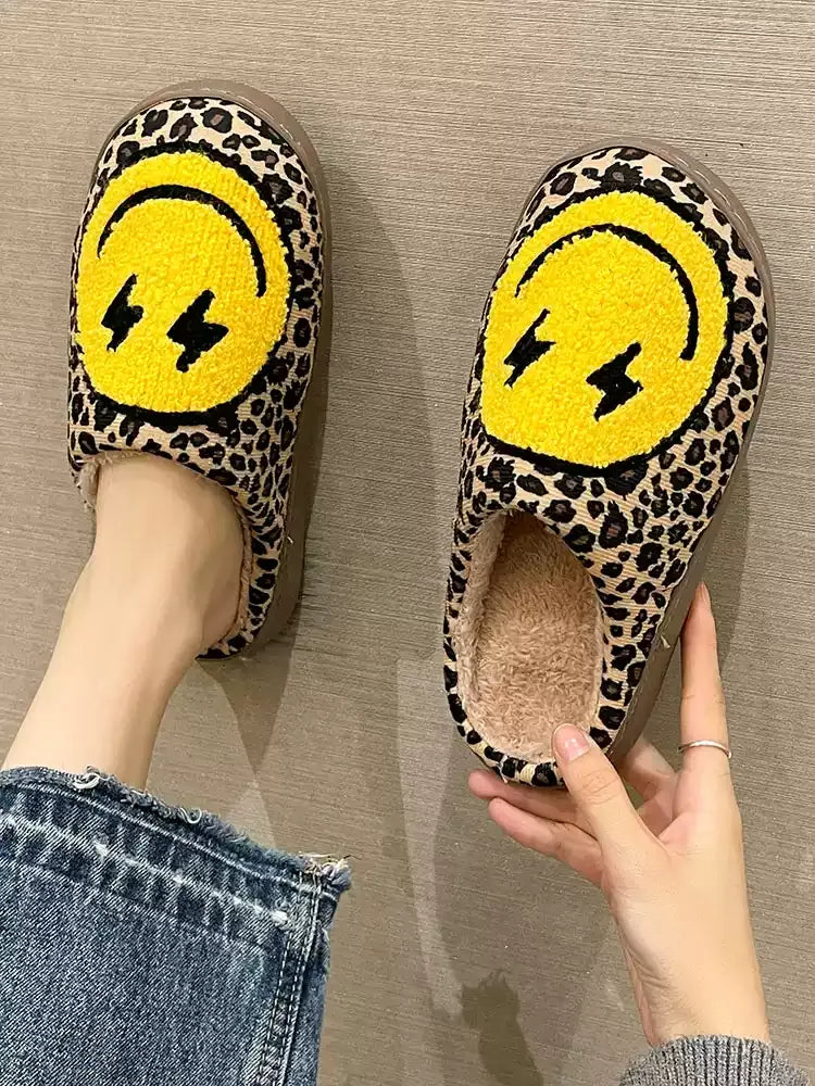 Leopard print slippers with yellow smiley face design on a neutral background