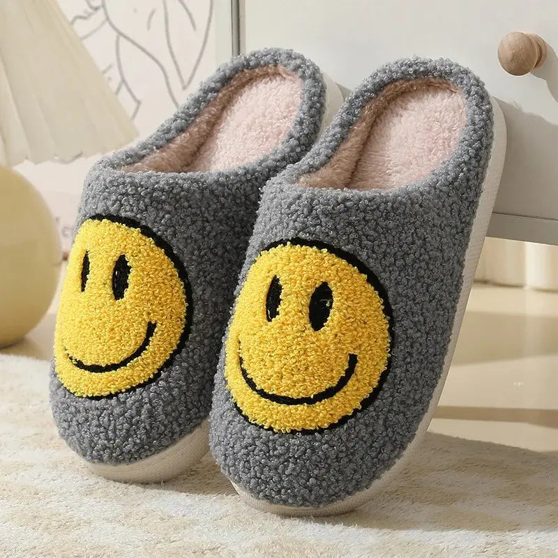 Gray slippers with yellow smiley face design on a soft surface