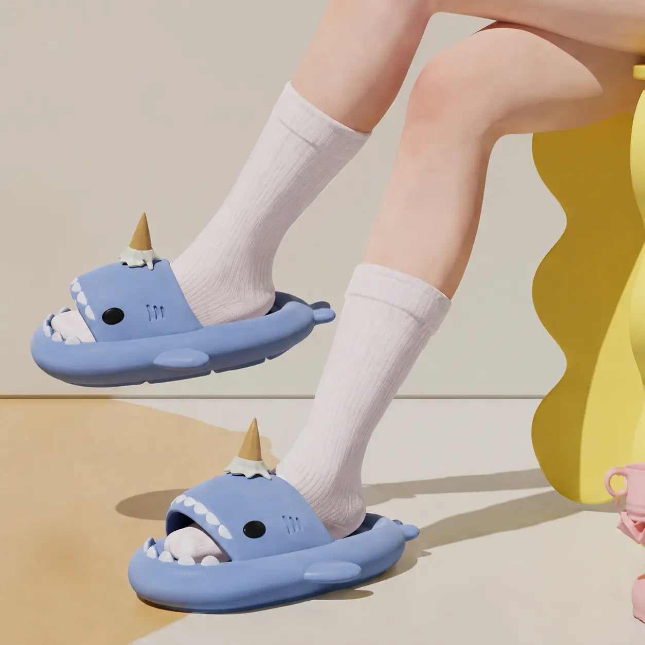 Blue cartoonish sandals worn with white socks on a neutral background
